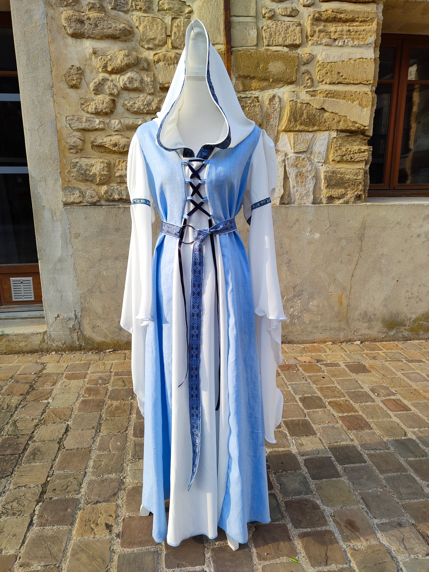 Robe médiévale bleue ciel et blanche avec sa ceinture et capuche, longues manches.