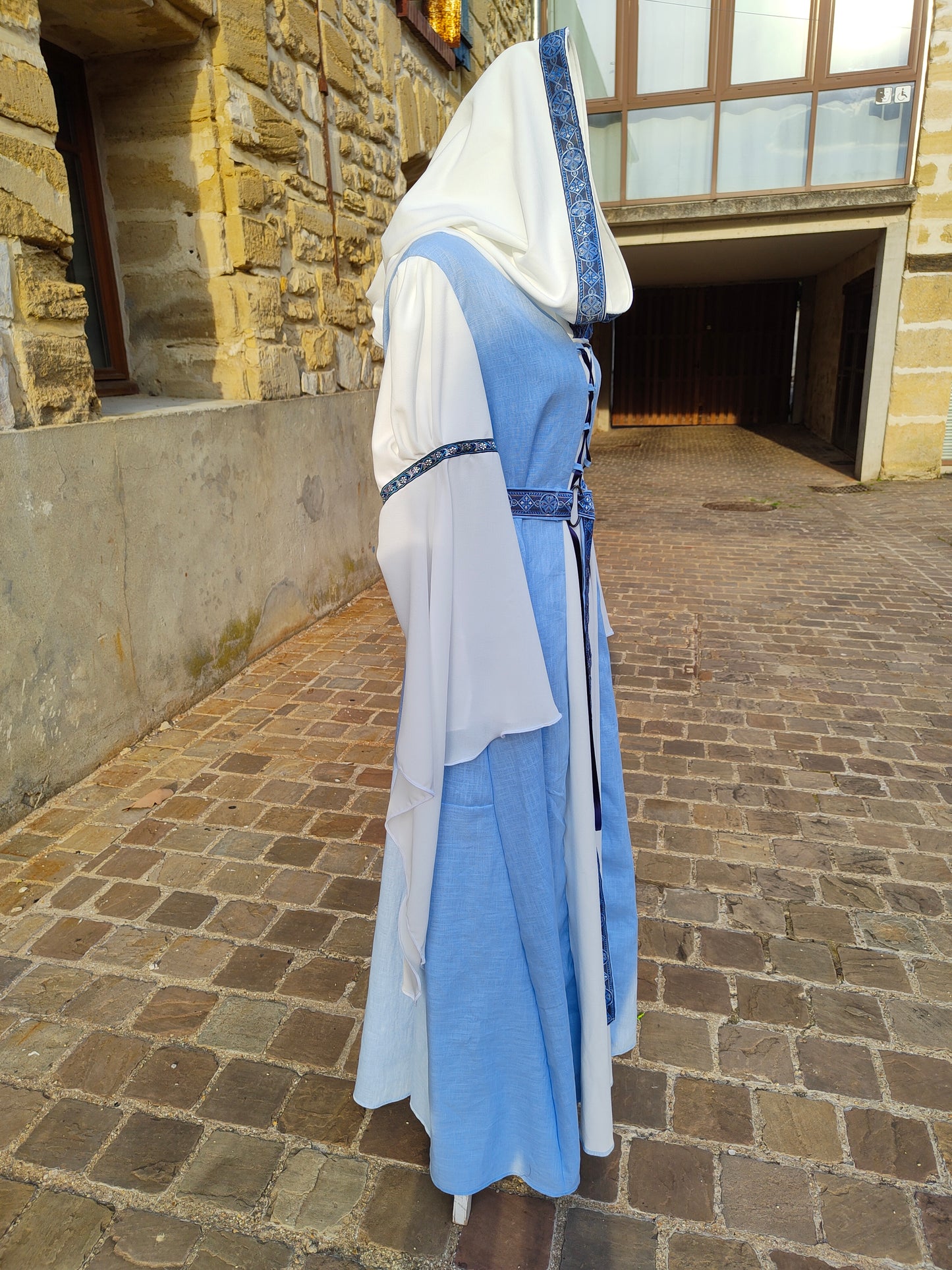 Robe médiévale bleue ciel et blanche avec sa ceinture et capuche, longues manches.