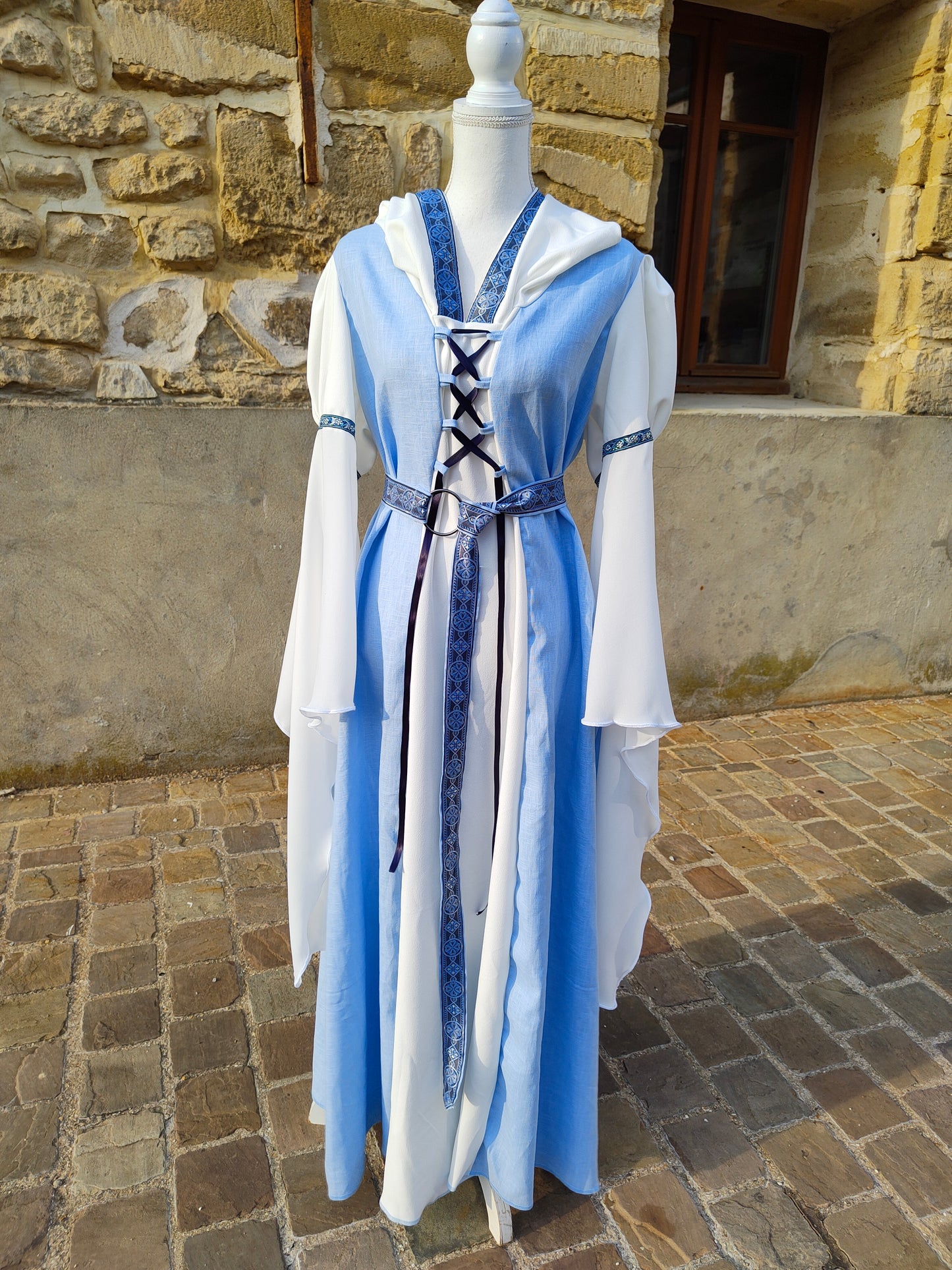 Robe médiévale bleue ciel et blanche avec sa ceinture et capuche, longues manches.